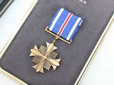 a gold medal and a blue and white ribbon in a case