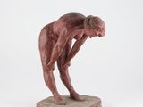 une sculpture représentant un homme penché sur un rocher