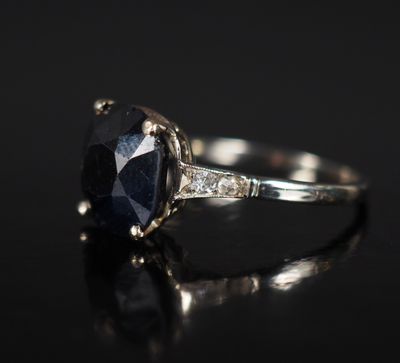 a close up of a sapphire and diamond ring on a black surface