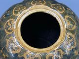 un grand vase vert orné de motifs dorés
