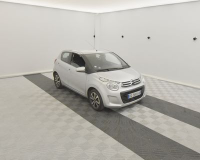 une petite voiture blanche garée dans une pièce dont le sol est en damier noir et blanc
