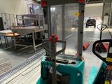 un chariot élévateur dans un entrepôt, avec une machine en arrière-plan