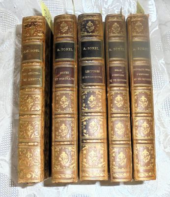 six old books are lined up on a white table cloth