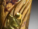 a close up of a vase with a gold decoration on it