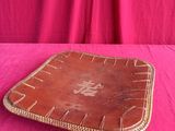 an old leather tray on a pink tablecloth with a pink background
