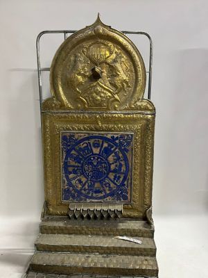 a gold and blue clock on display on a white surface