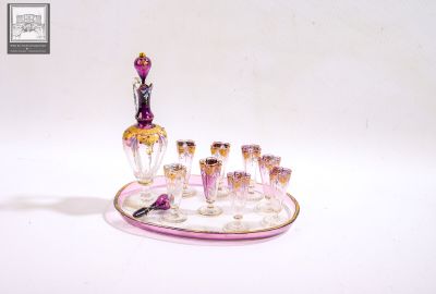un verre à vin posé sur un plateau avec une bouteille et des verres