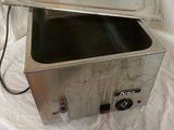 a small stainless steel container with a lid on a white sheet