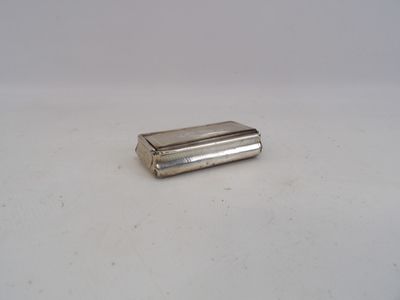 un petit briquet argenté posé sur une surface blanche