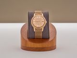 une montre en or posée sur un socle en bois, sur une table