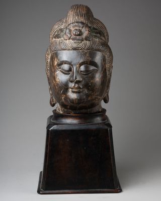 a carved head of a buddha on a wooden stand