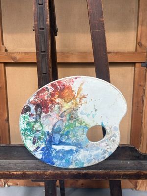 une palette de peinture posée sur une chaise devant un chevalet
