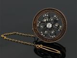 un gros plan d'une broche en or et diamants suspendue à une chaîne