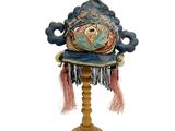 un chapeau bleu posé sur un support en bois, sur fond blanc