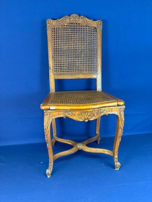 une vieille chaise en bois avec une assise en osier, sur fond bleu