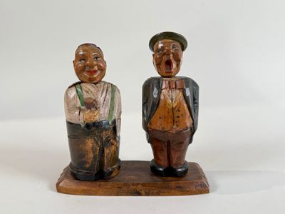 pair of wooden figurines of two men standing on a wooden base