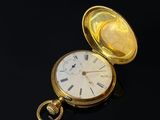 montre de poche posée sur un fond noir, avec un boîtier doré et des chiffres romains