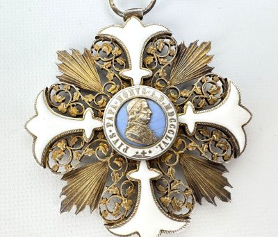a white and gold medal with a blue picture on it