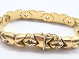 bracelet made of gold plated metal with a clasp on a white background