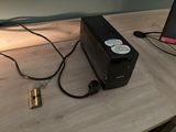 a black power supply sitting on a desk next to a laptop computer
