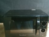 un petit micro-ondes noir posé sur une table en bois