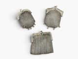 three silver metal mesh purses on a white surface