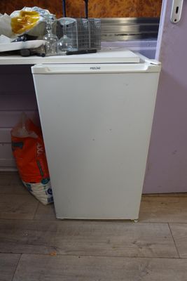 un petit réfrigérateur blanc dans le coin d'une cuisine