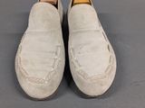 pair of men ' s white sued slippers with leather soles on a gray surface
