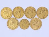 six gold sovereigns of different sizes and shapes on a white surface
