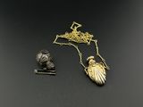 deux bijoux posés sur un fond noir, avec un collier plaqué or