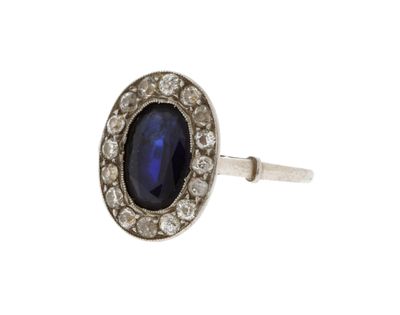 gros plan d'une bague avec une pierre bleue entourée de diamants
