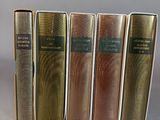 five books are lined up in a row on a gray surface