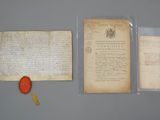 two old papers and a red paddle sit on a table