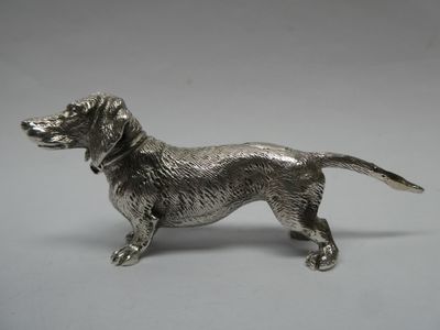 une figurine antique en argent représentant un chien, sur fond blanc