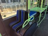 a green and blue seat on a bus next to a window