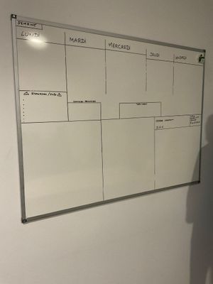 un homme debout devant un tableau blanc sur lequel figure un calendrier
