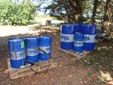 several blue barrels sitting on top of a wooden pallet next to a forest