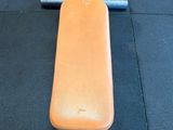 an orange bench sitting on the floor in the gym