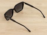 black sunglasses on a wooden surface with a white background