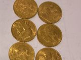 six gold coins are sitting on a white surface
