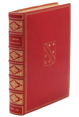 un livre rouge aux bords dorés, avec un emblème doré sur la couverture