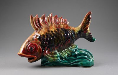 un poisson en céramique perché au sommet d'une vague