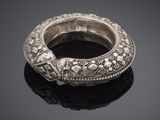 an antique silver bangle with floral designs on a black surface