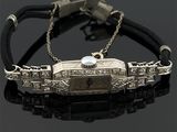 une image représentant un bracelet sur lequel est posée une montre, sur un fond noir