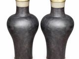 pair of black vases with gold lids on a white background