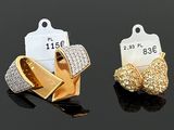 quatre types de boucles d'oreilles différents, accompagnés de leurs étiquettes de prix, posés sur une surface noire