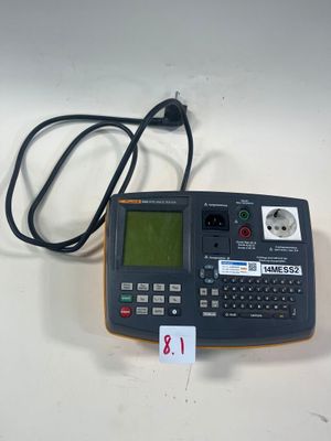 une calculatrice posée sur une table, à laquelle est relié un cordon