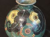 a green vase with a design on it on a black background