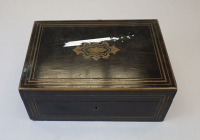 une vieille boîte noire ornée d'un motif doré sur le couvercle