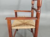 an image of a wooden chair with a woven seat on a gray surface